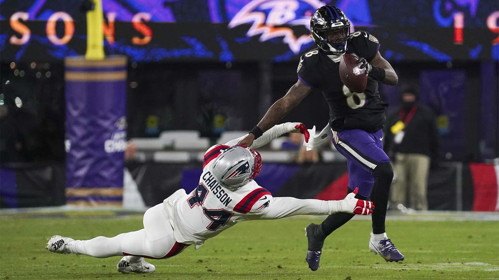 Baltimore Ravens quarterback Lamar Jackson (8) stiff arms New England Patriots linebacker K'Lavon Chaisson (44) during the first half of the game at M&T Bank Stadium.