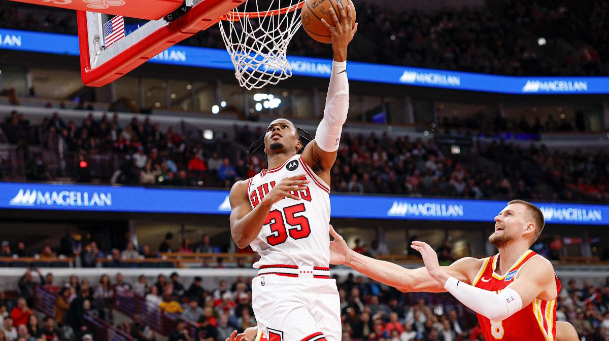 Oct 27, 2025; Chicago, Illinois, USA; Chicago Bulls forward Isaac Okoro (35) goes to the basket against Atlanta Hawks center Kristaps Porzingis (8) during the first half at United Center. Mandatory Credit: Kamil Krzaczynski-Imagn Images