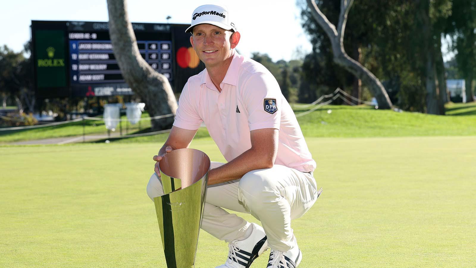 Jacob Bridgeman celebrates with the trophy on the 18th green after his win during the final round of the The Genesis Invitational golf tournament at Riviera Country Club.